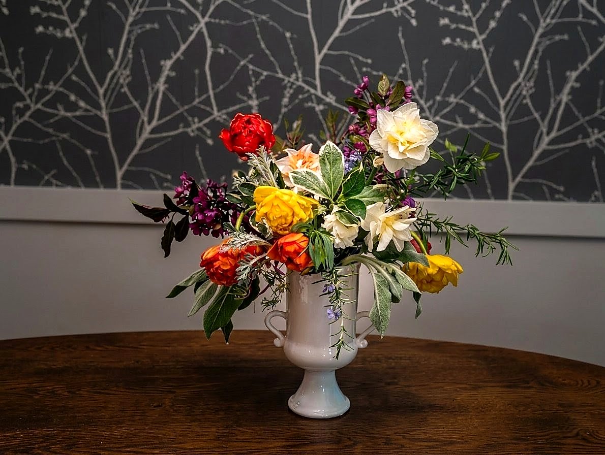 Spring centerpiece — peonies, daffodils, and lilac in a white footed urn