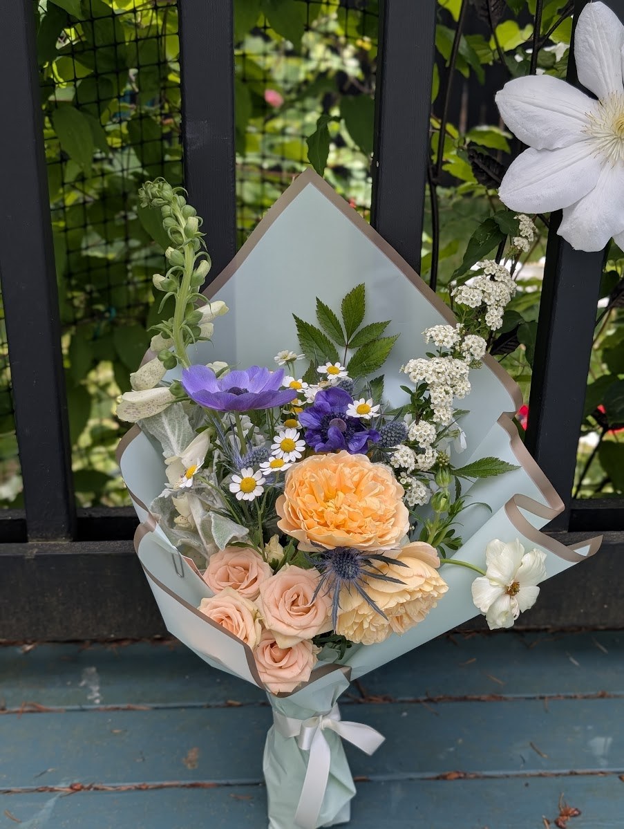Recital bouquet in peach and lavender — peach garden roses, butter ranunculus, lavender anemones, chamomile, and snapdragons